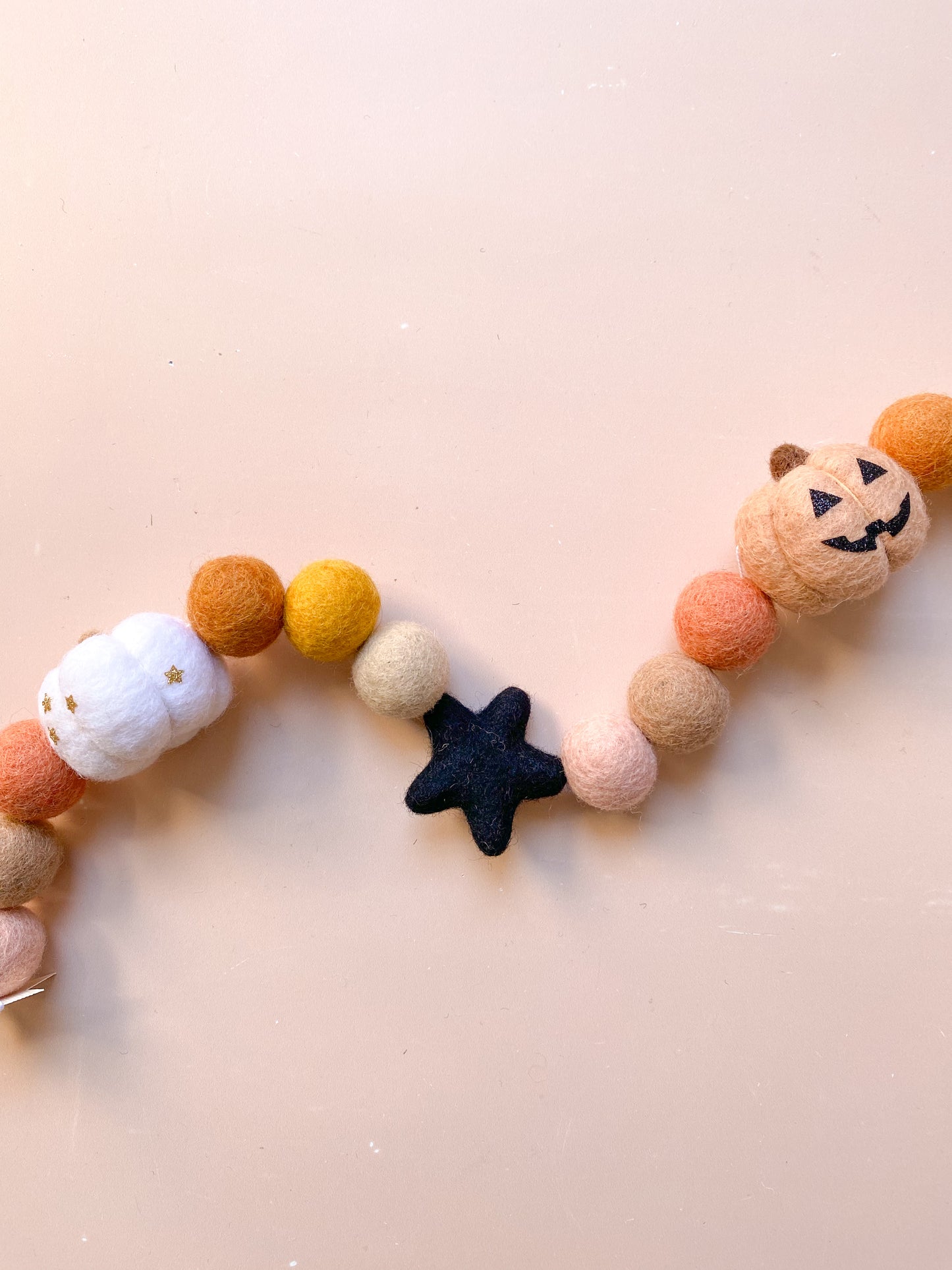 Decorative Halloween garland with felt balls, ghost with witch hat, jack o lantern pumpkin in fall colours