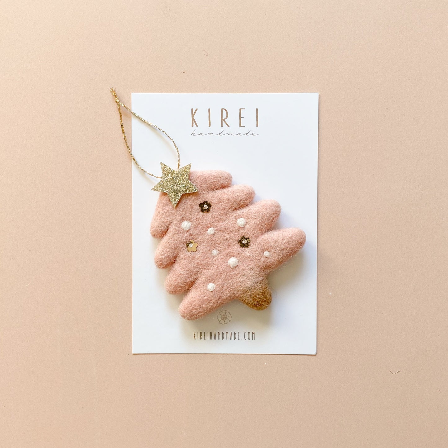 A pink felt Christmas ornament with a star and small decorative details, attached to a gold glitter string,