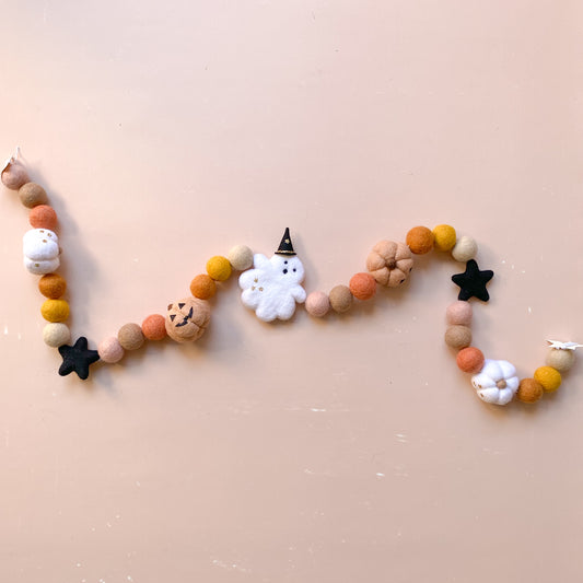 Decorative Halloween garland with felt balls, ghost with witch hat, jack o lantern pumpkin in fall colours