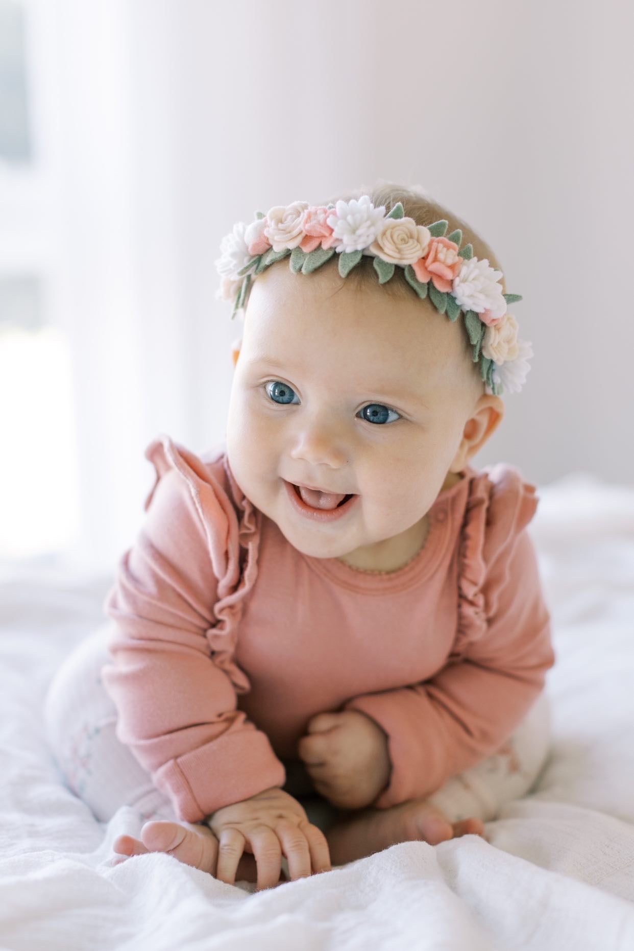 a baby girl smiling wearing handmade pink felt flower crown