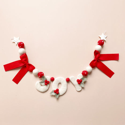 Decorative wool felt garland with word 'JOY' with red bows and berries 